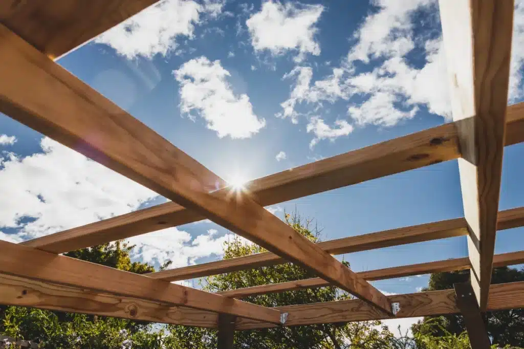 Structure en bois de pergola avec vue sur le ciel bleu, idéale pour un aménagement extérieur chaleureux et durable